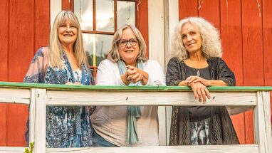 Three women behind a railing staring out