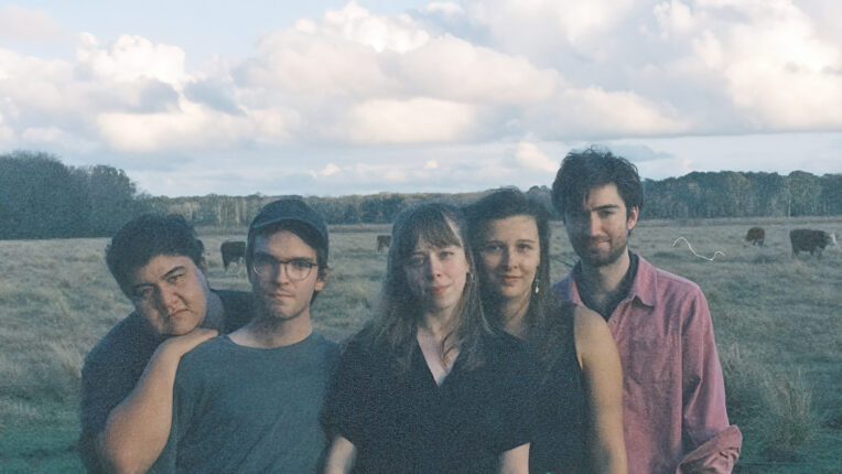 Five people in the middle of a field with cows in the background