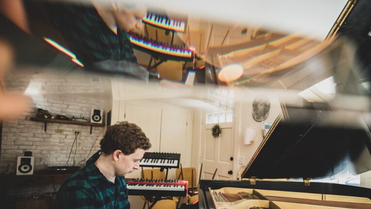musician seated at piano with reflection of mirror on the ceiling