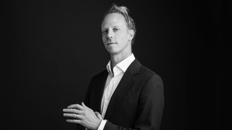 Black and white images of man in suit standing with hands in front