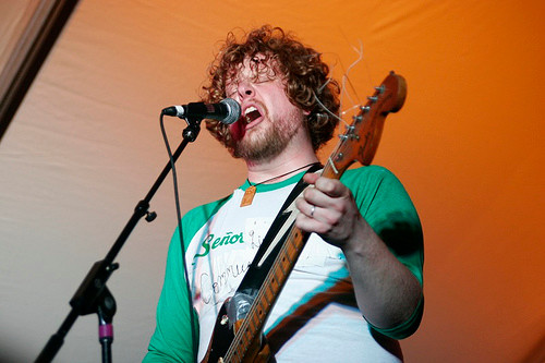 Jason Groth sings into a microphone and plays guitar.