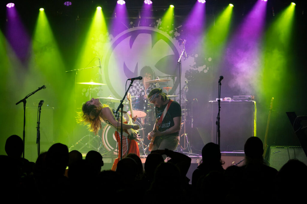 Musicians on lit stage with one bent backwards