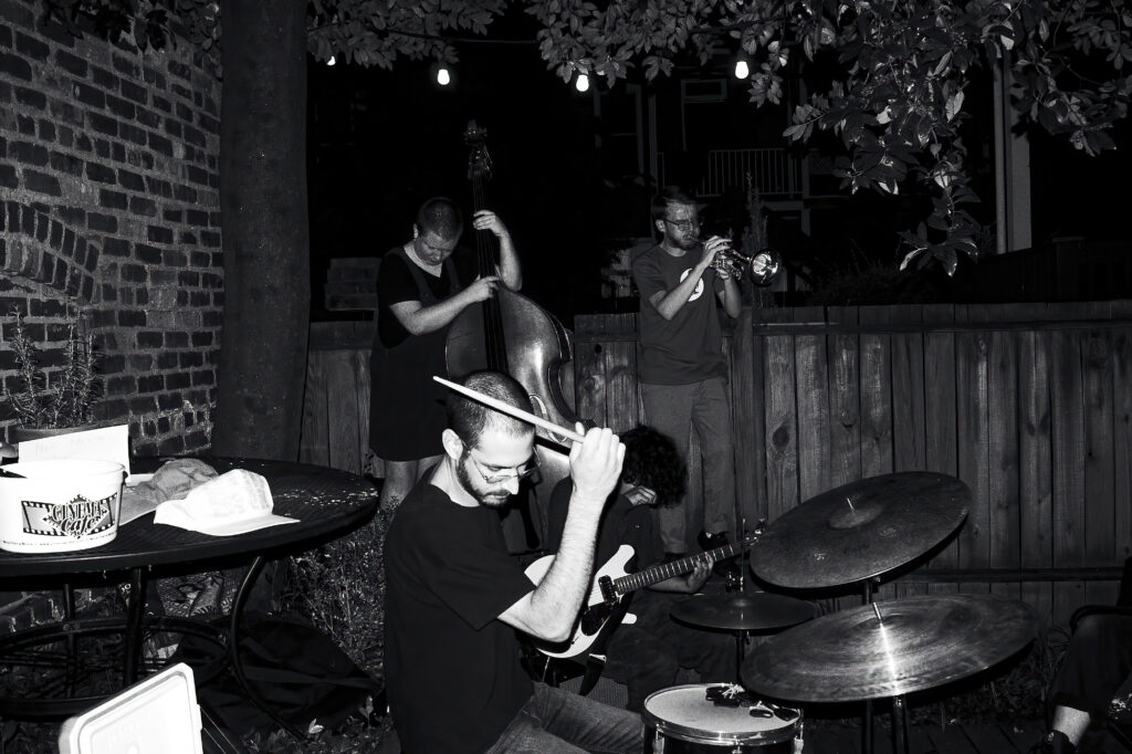 black and white photo of four musicians playing outside in the night