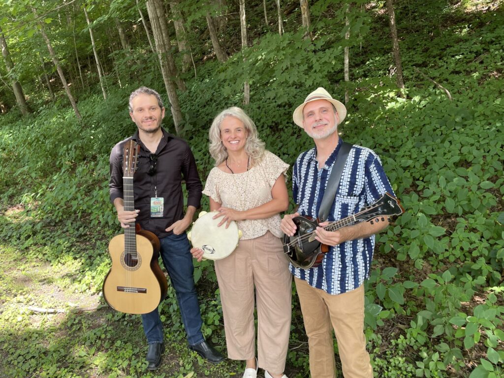 Two men and a woman holding instruments out in the woods
