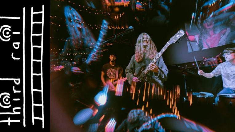 Sylized image of musicians and lights. Valentin Prince holds a guitar at the center of the image with a drummer to the right.