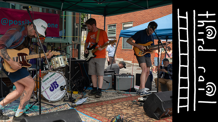Real Companion, a band from North Carolina, plays music outdoors, under a tent.