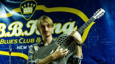 Young musician holding up a National Reso-Phonic NRP Steel Tricone resonator guitar