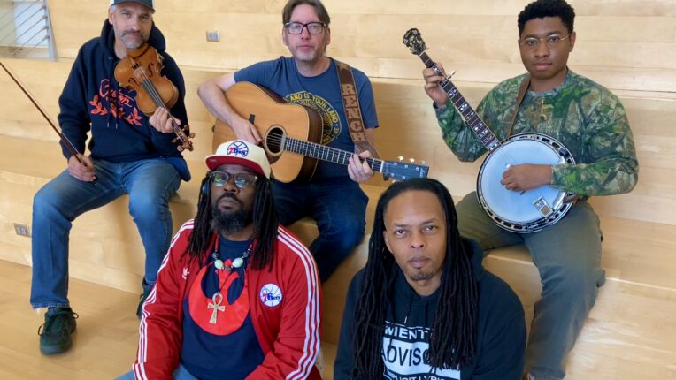 Five men, home holding instruments, seated