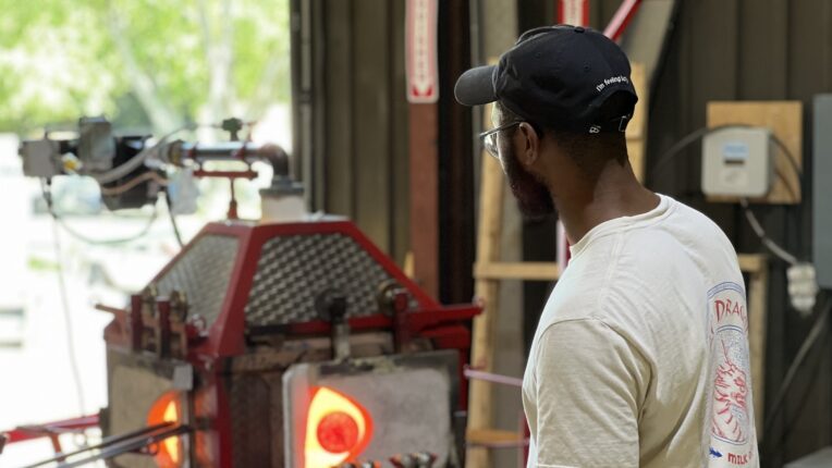 Image of man heating glass in a forge.