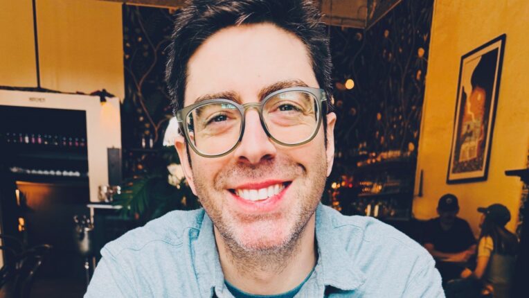Author Josh Mound sits with arms crossed and smiles for the camera