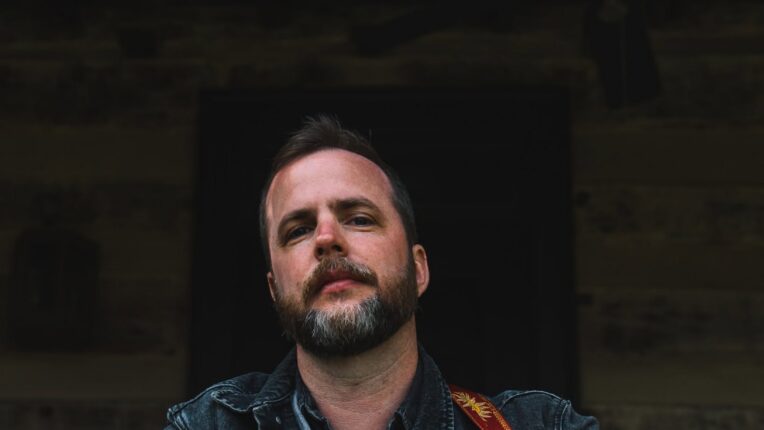 Musician Brennan Gilmore with a seated with a guitar