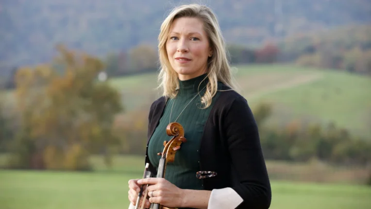 Violinist Rachel Yonan stands outside with a autumnal backdrop