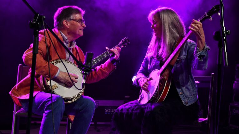 Bill and Babi Evans holding banjos as they look at each other