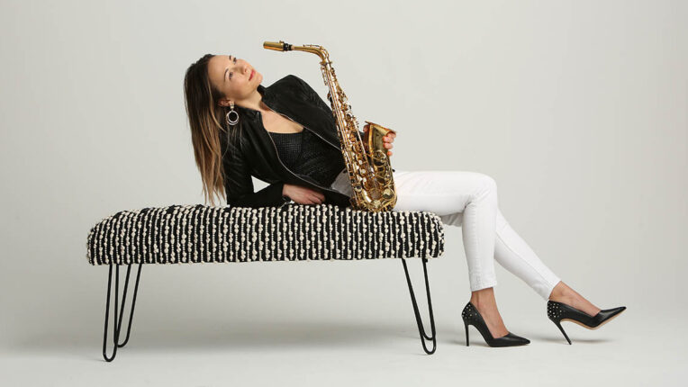 Sharel Cassity lays back on a plush bench with her saxophone.