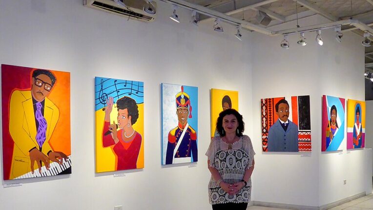 Artist Mirta Toledo standing in front of her art in a gallery.